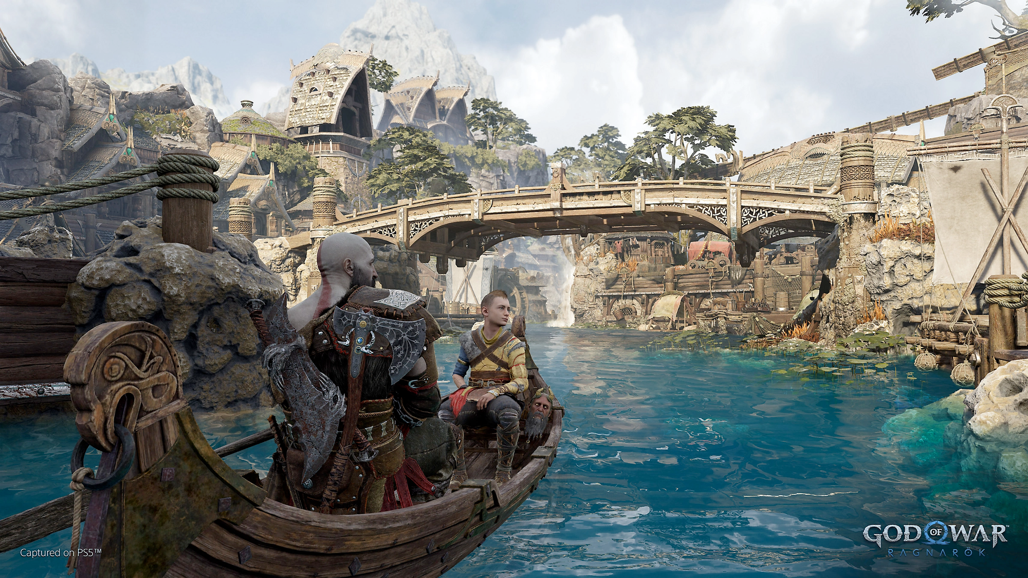 God of War Ragnarök screenshot showing Kratos and Atreus on a boat in a blue river, in a rocky village