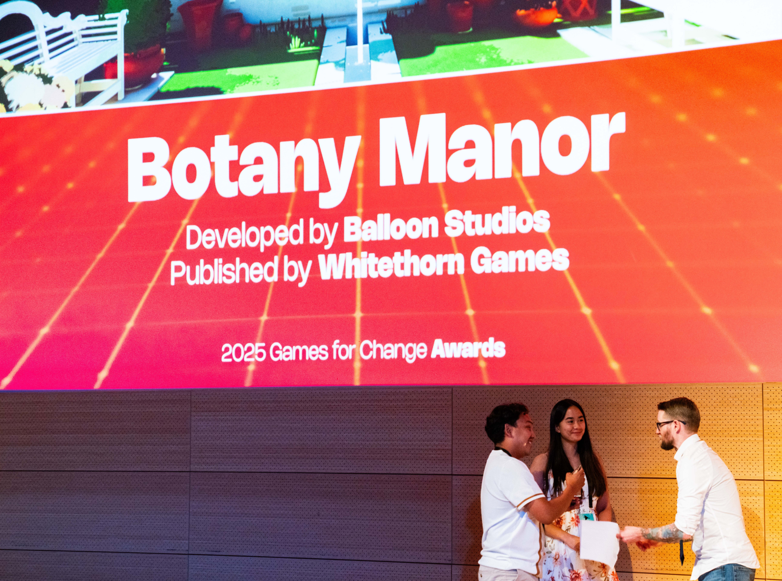 Baloon Studios accepting award at Games For Change festival, in front of large video screen.